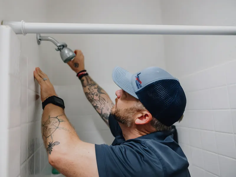 Technician installing shower head, from American Plumbing Co.’s own photographs.