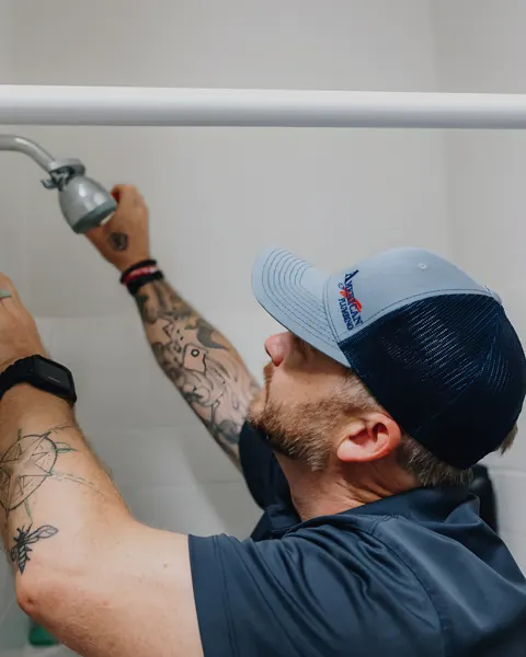 Technician installing shower head, from American Plumbing Co.’s own photographs.