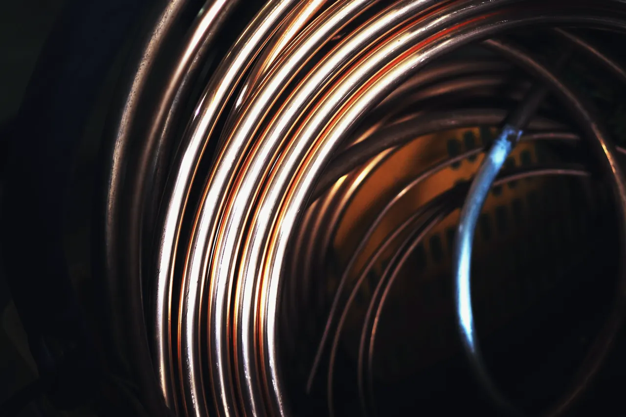 A coil of copper tubing, close up, on black.
