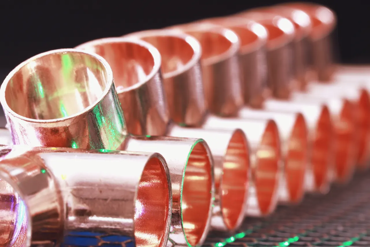 A row of new copper pipe couplings, in shallow focus.