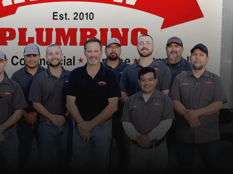 Nine members of the crew in company shirts stand in front of a white box truck.