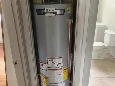 A new gas water heater installed in a narrow closet beside a bathroom.