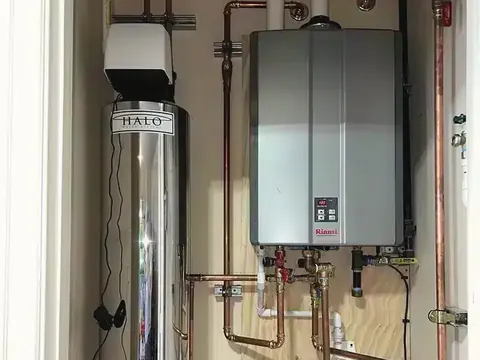 A tankless water heater and a stainless water-filtration tank installed side by side in a closet.