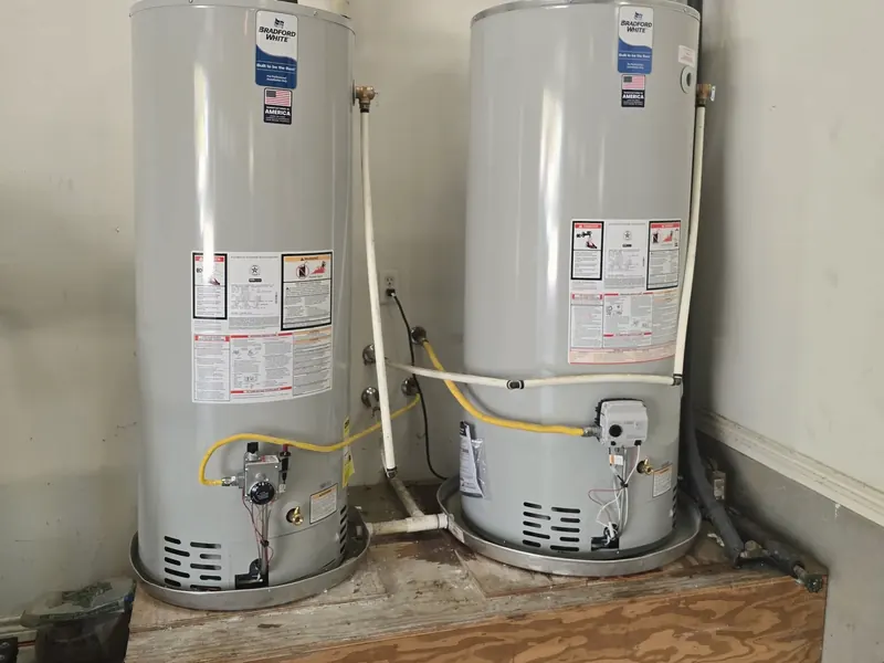 Two gas water heaters on a raised wooden platform, with new venting and gas lines.