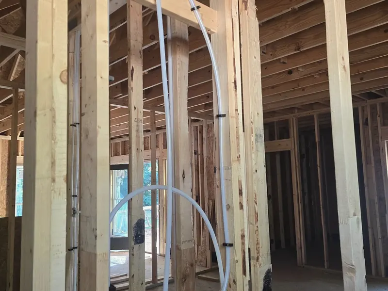 A shower valve and PEX lines roughed in on a framed wall in a house under construction.