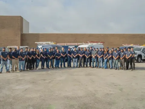 The company crew, about forty people in navy shirts, lined up in front of their service trucks.