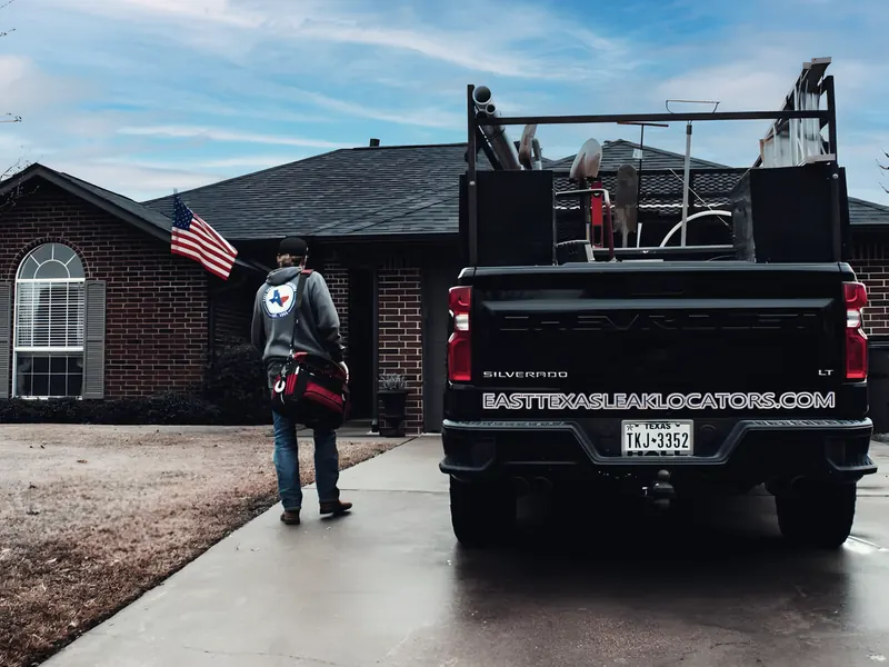 Technician walking to job with branded company truck, from East Texas Leak Locators & Plumbing Services’s own website.